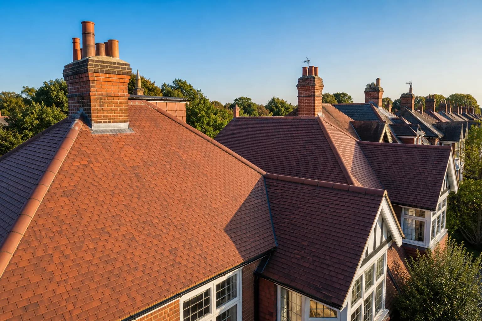 Newly tiled pitched rooftops of traditional British homes under a clear blue sky